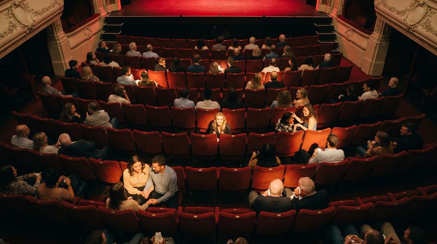 Audience seated in a theatre with empty seats still to fill